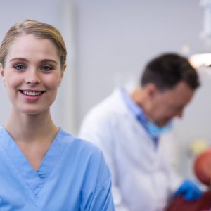 Smiling dental assistant standing in dental clinic